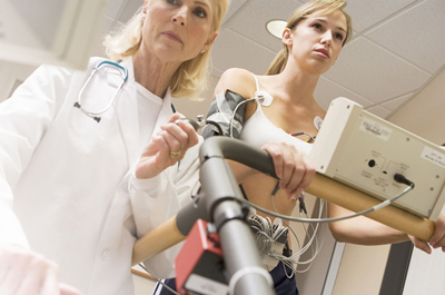 Patient in action of completing a stress test with the help of a technologist.