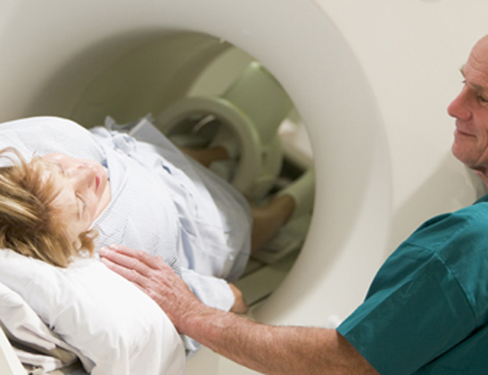 Patient preparing for a CAT scan with the help of a technologist.